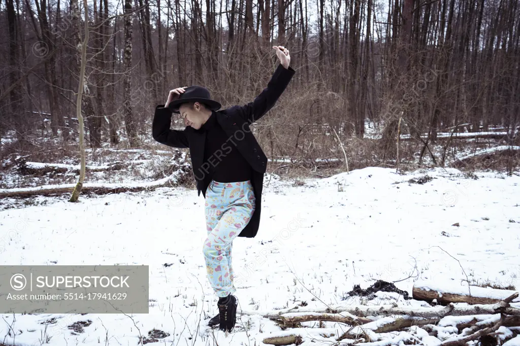 Androgynous dancer in bright blue pants dances in snow in Germany