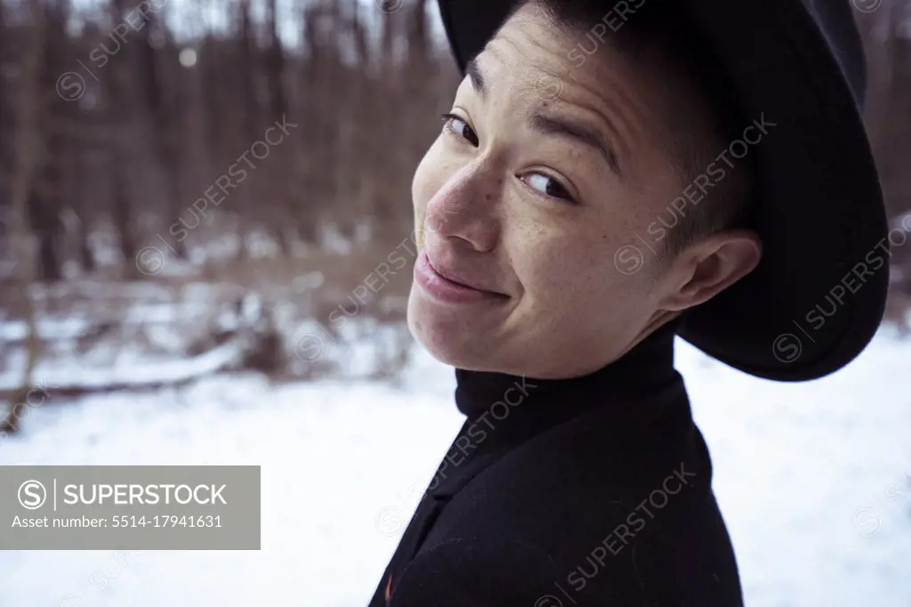 big cheeky smile from mixed-race person in black hat on white snow