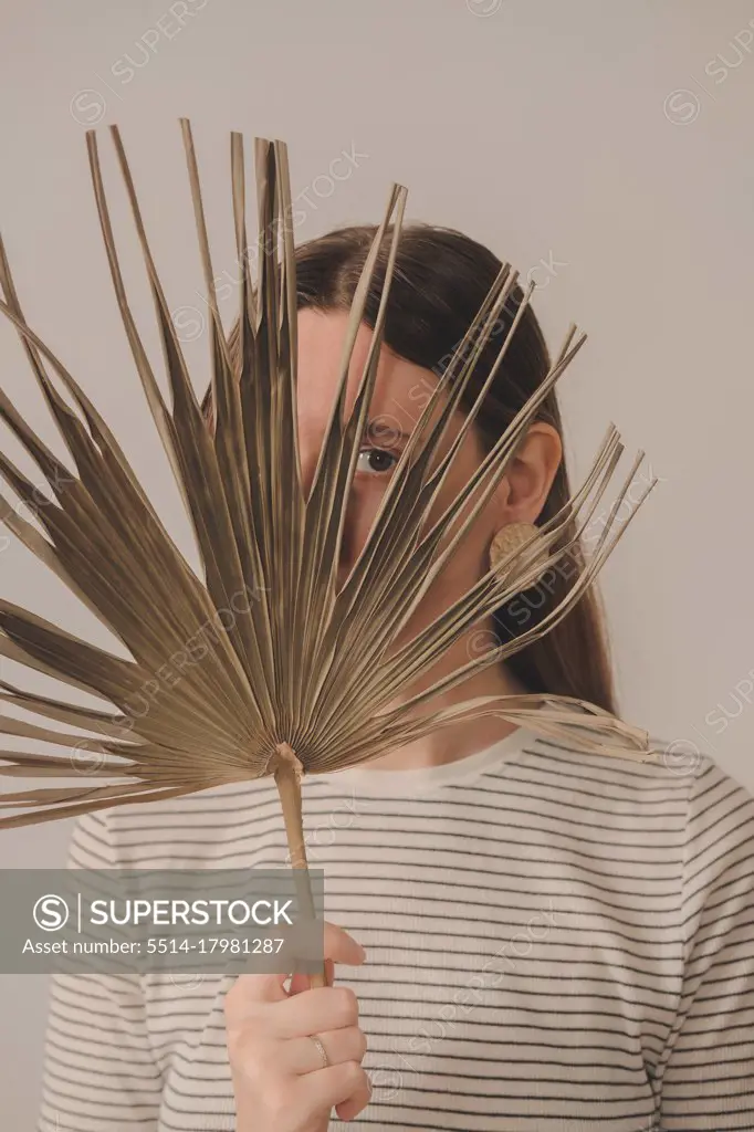 Portrait of a woman looking through a palm leaf. Young caucasian