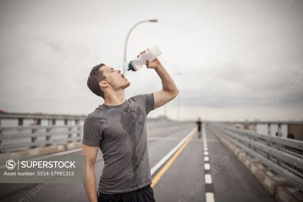 Male athlete pouring water trying to rehydrate during workout