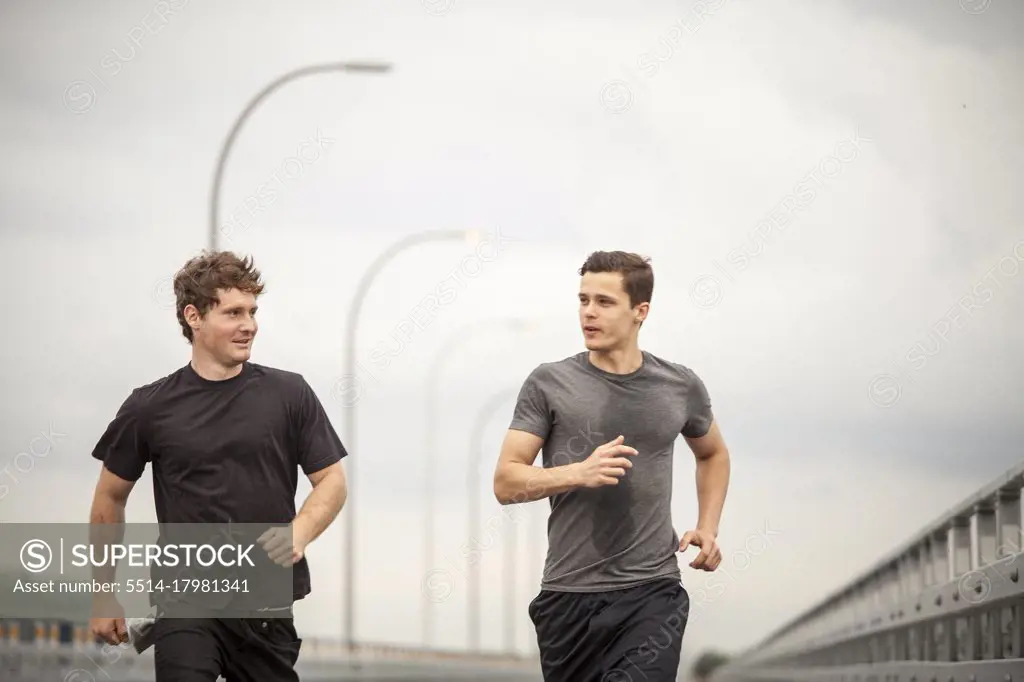 Supportive male athletes running together during workout outdoor
