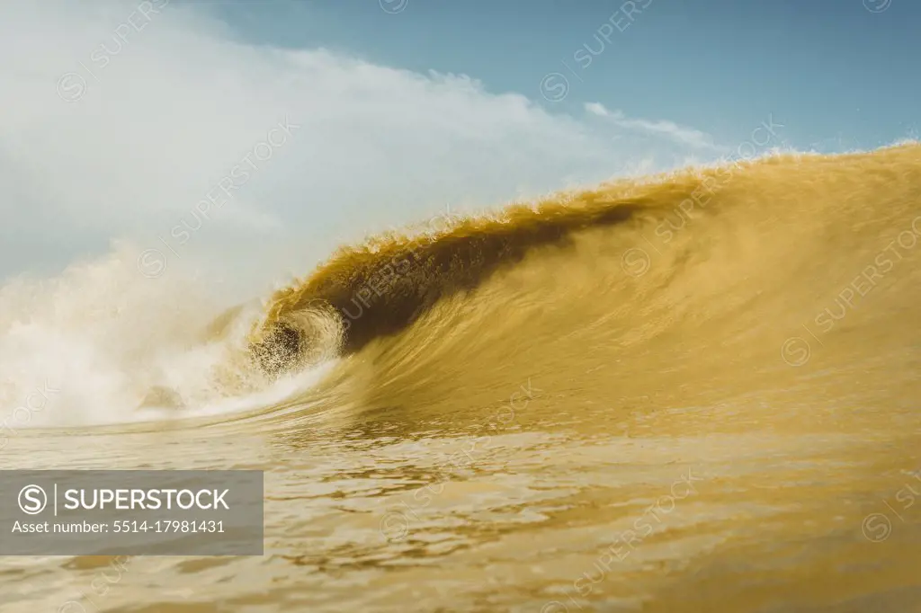 Brown wave breaking into the sea, shot from the water
