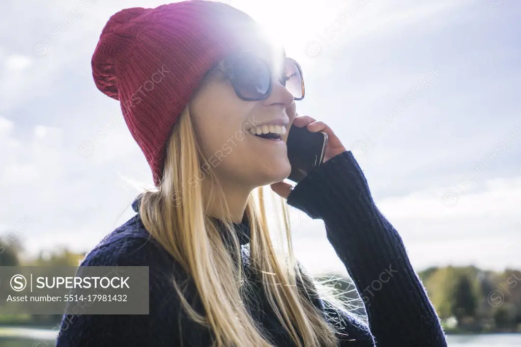 Young blonde woman in park making a phone call with happy expres