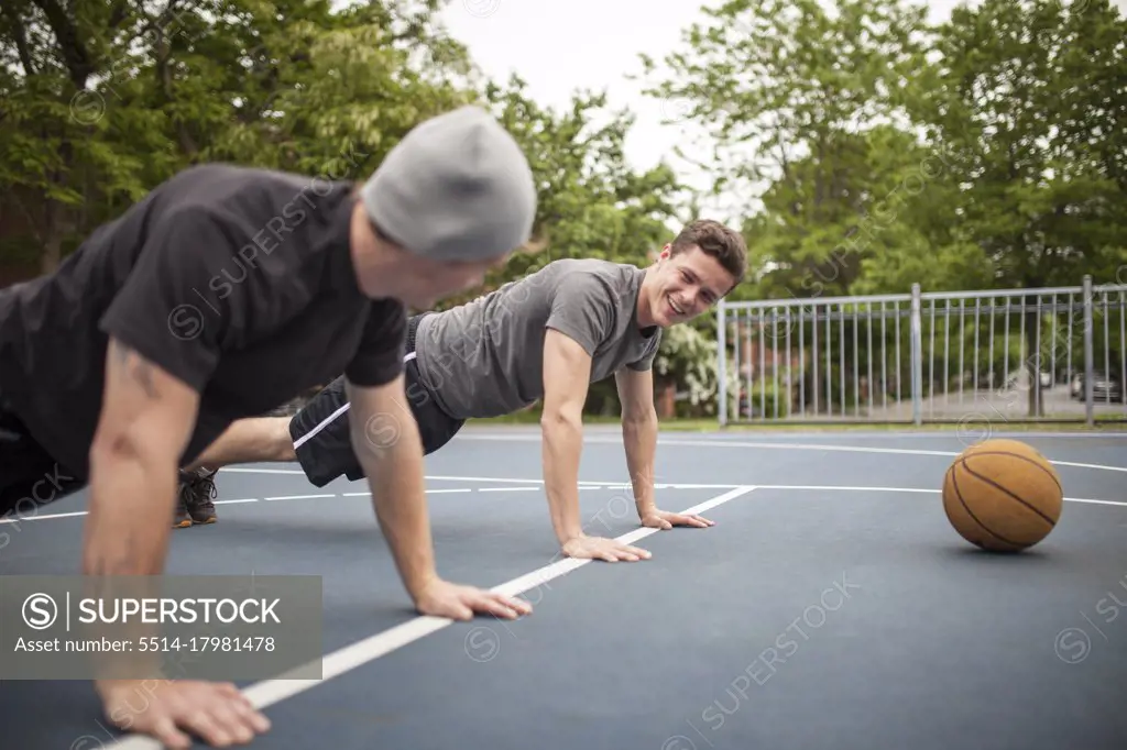 Friends doing push-ups before game in basketball court