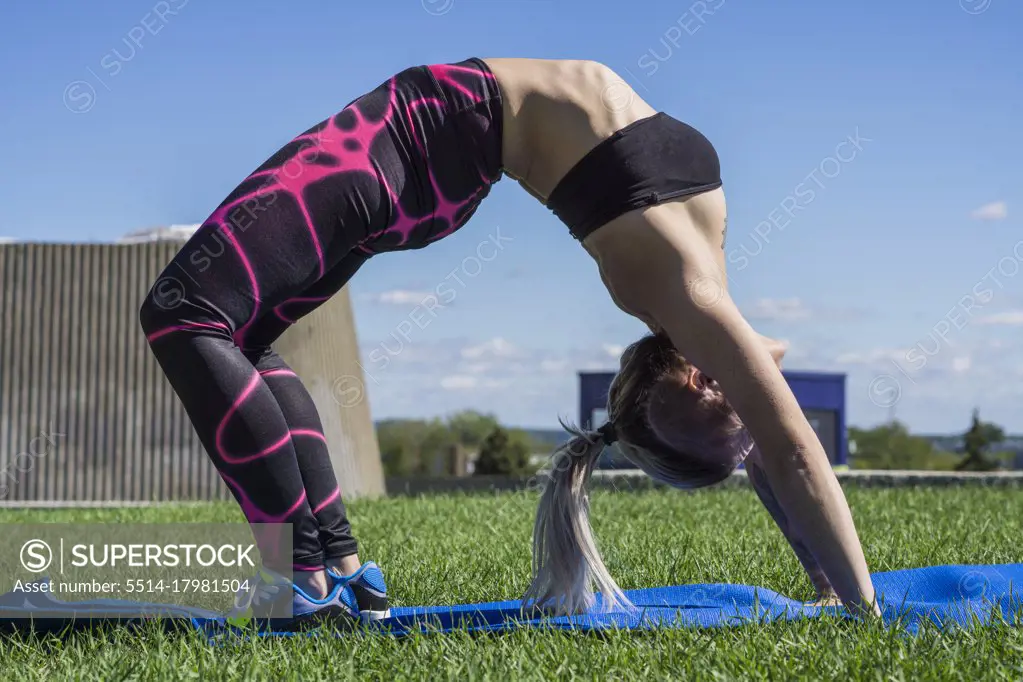 Young female athlete doing chakrasana yoga pose