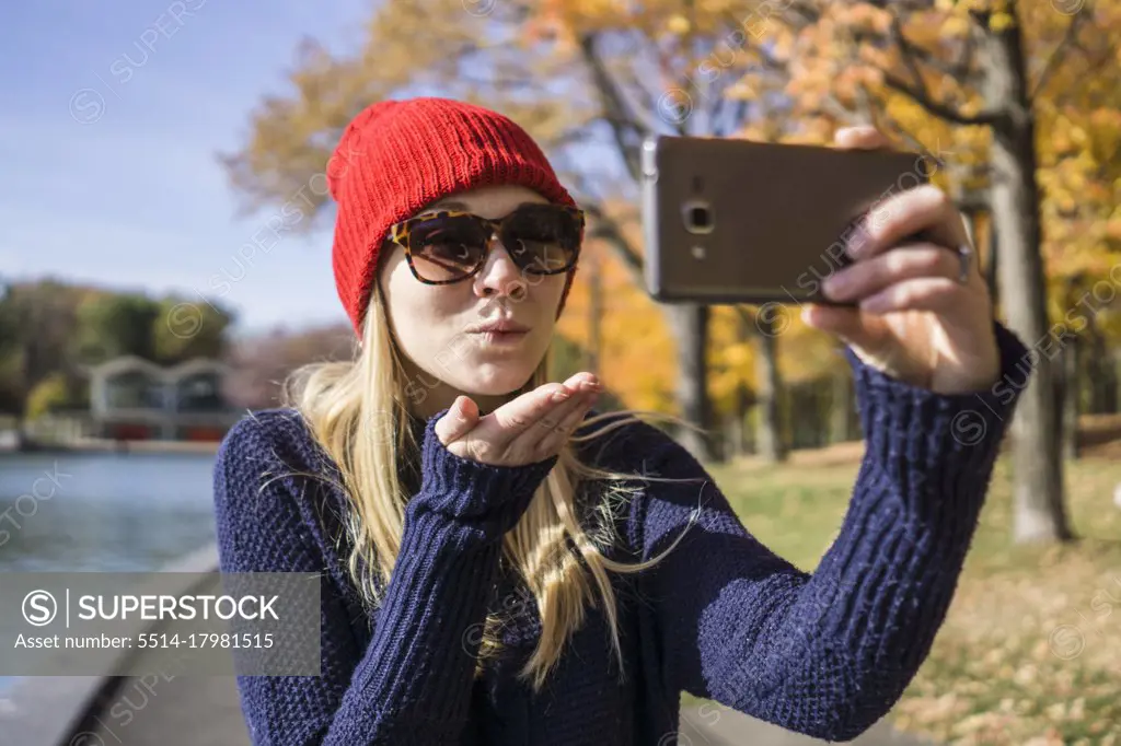 Canadian woman in park using smartphone to take selfie