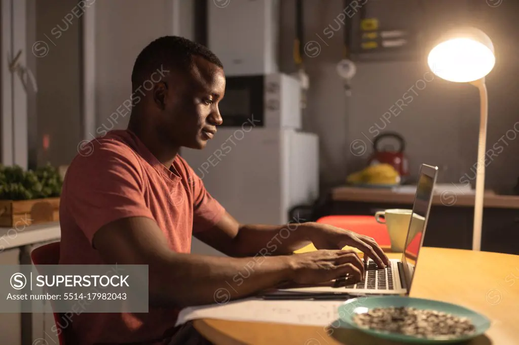 African American freelancer using laptop in kitchen