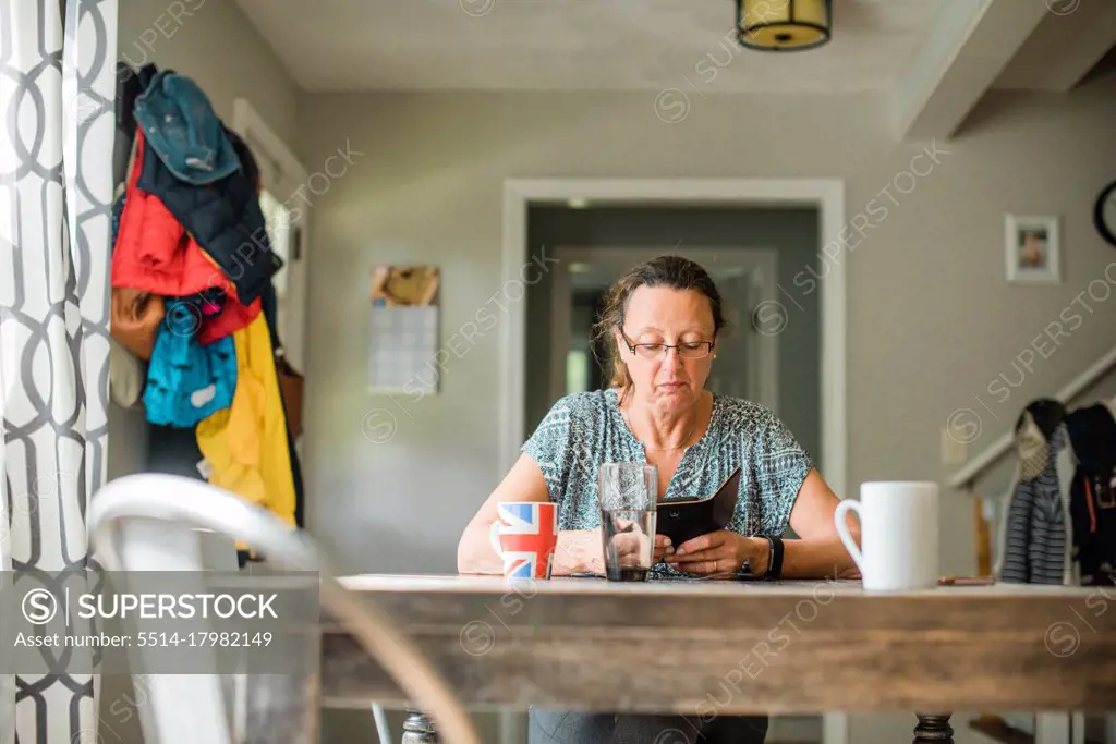 middle aged woman looking on her smart phone and having coffee