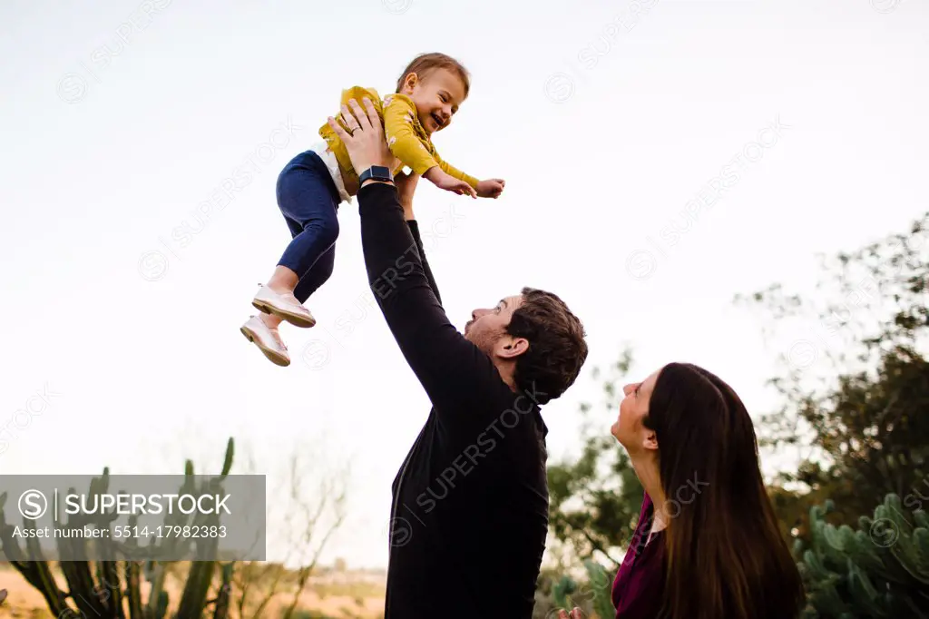 Dad Lifting Smiling Daughter as Mom Watches in San Diego