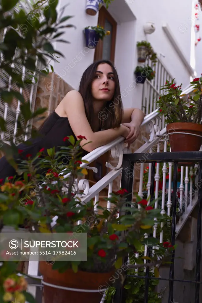 Young teenage girl leaning on the stairs of the flowery patio of