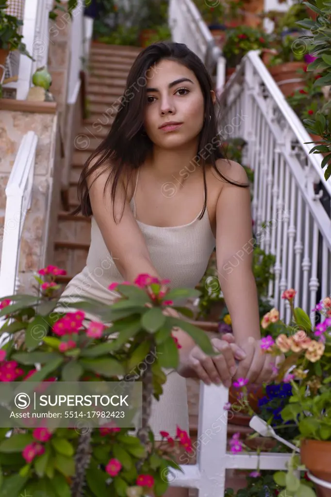 Pretty teenage girl looks at the camera among the flowers of her