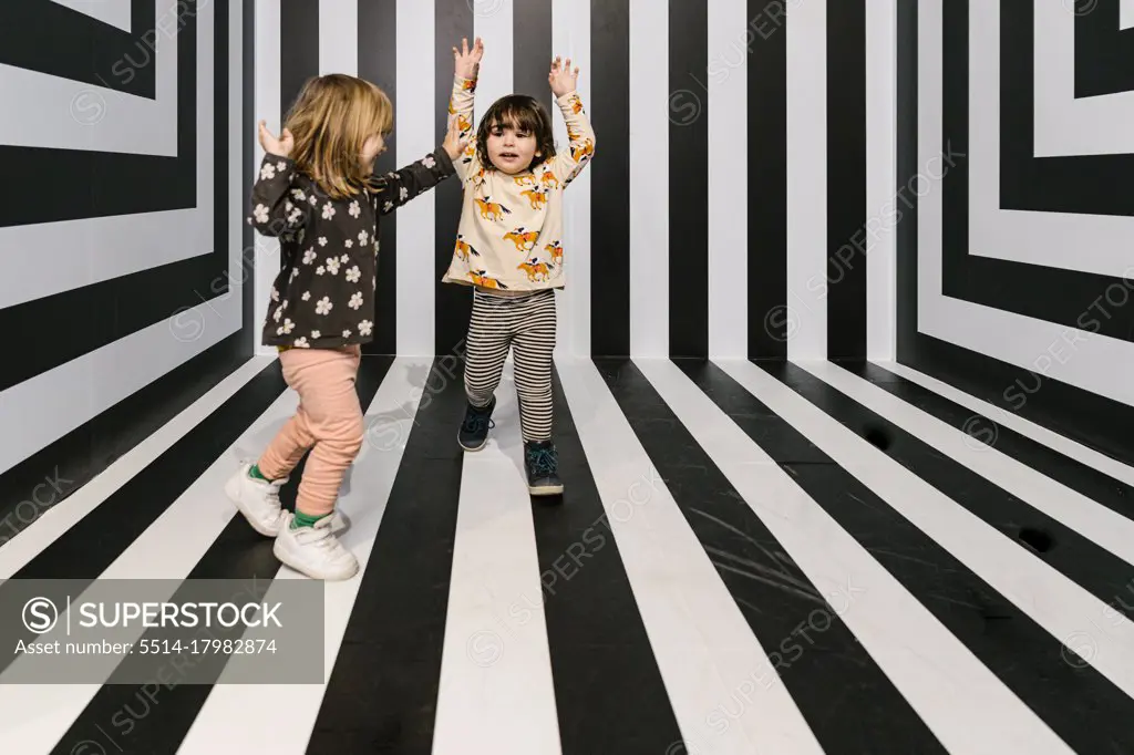 Two little girls having fun and playing together while standing on a s