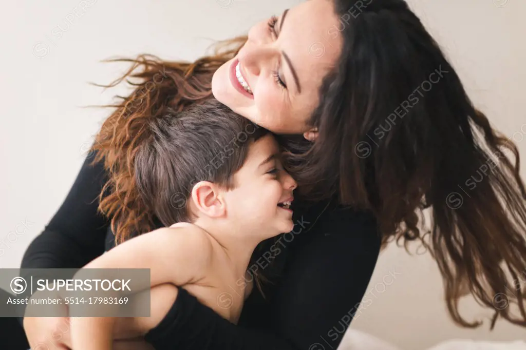 Mother and son hugging each other and laughing.