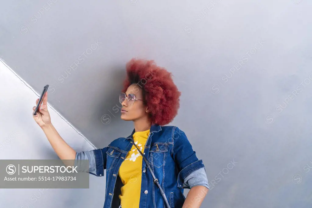 woman with red afro hair taking a picture