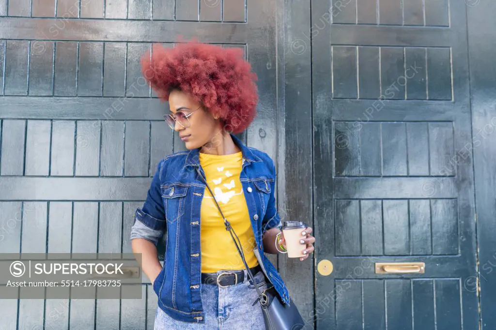 woman with red afro hair having her coffee in the street