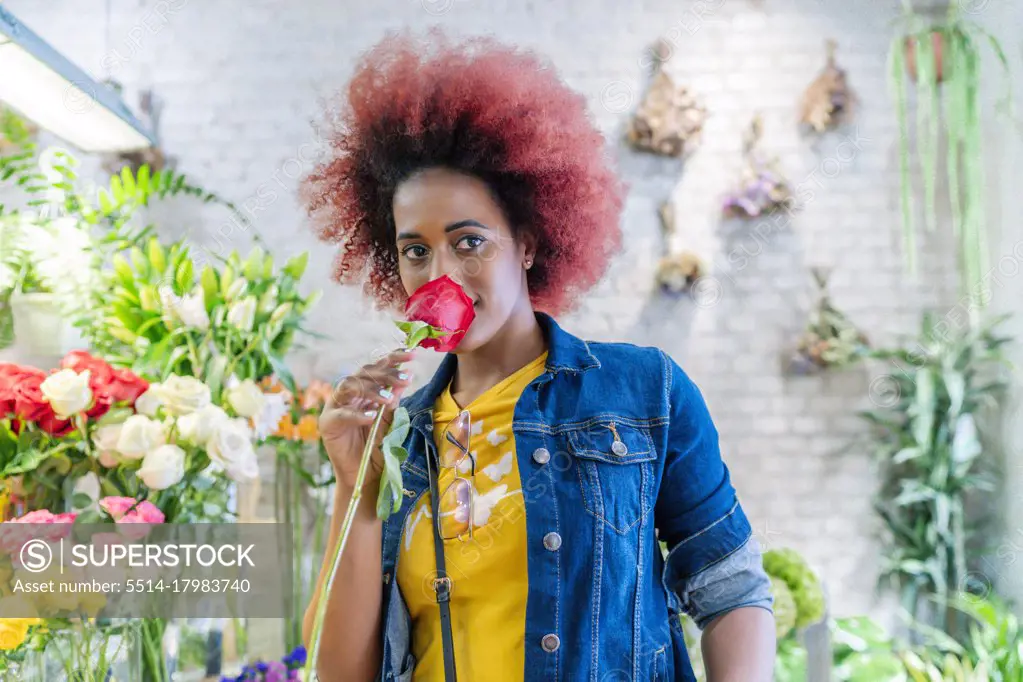 woman with afro hair smelling a pretty rose