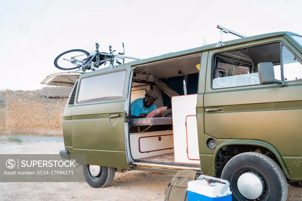 black afro american male person inside his camper van, freedom and tra
