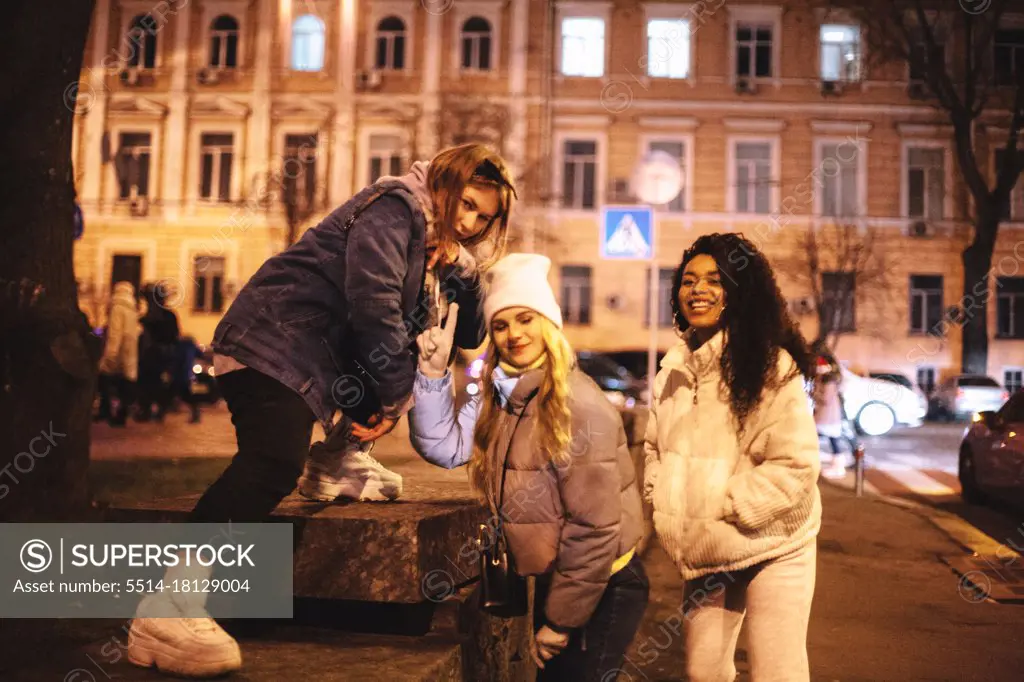 Happy female friends having fun in city at night