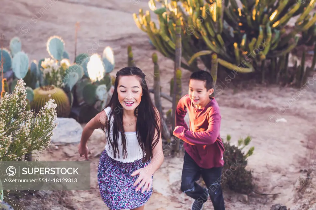 Brother and sister playing tag at a cactus garden.