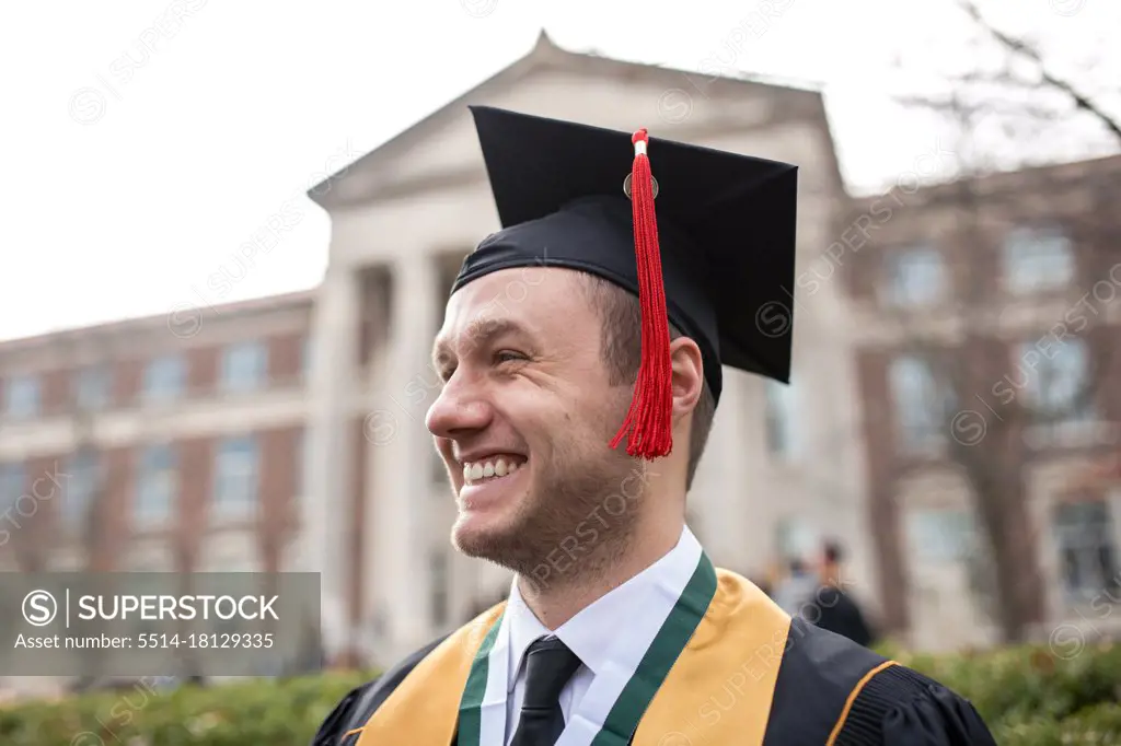 Portrait of proud young man in graduation cap and gown