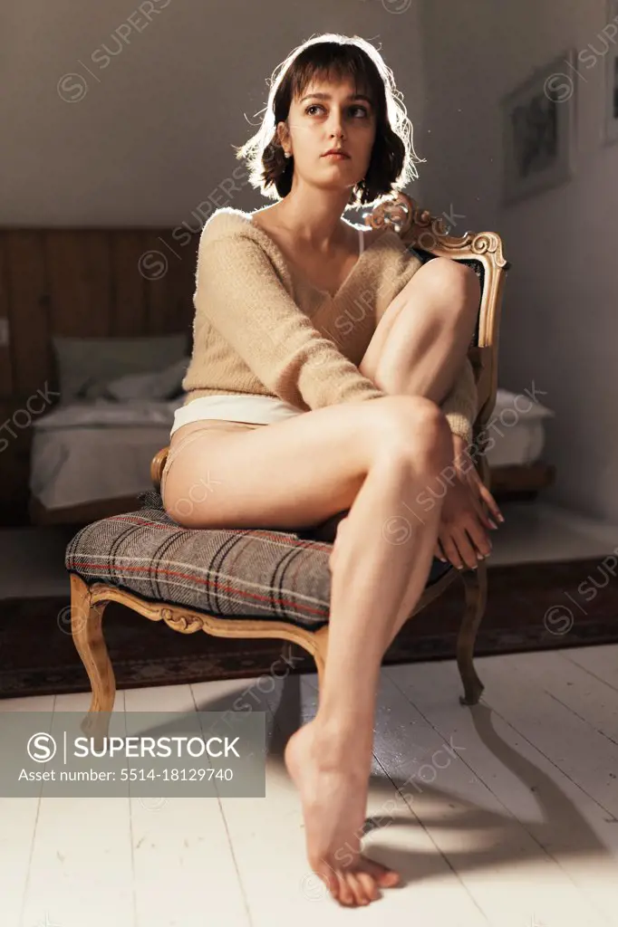 sad woman sitting on a chair in panties - SuperStock