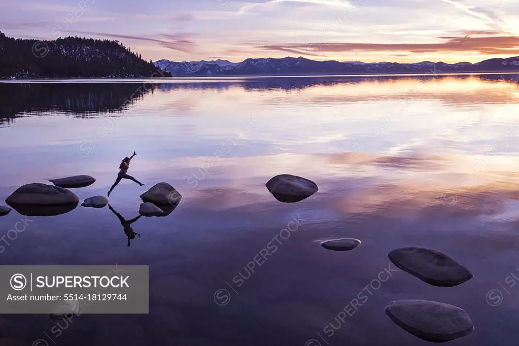 Female jumping from rock to rock at sunset on Lake Tahoe
