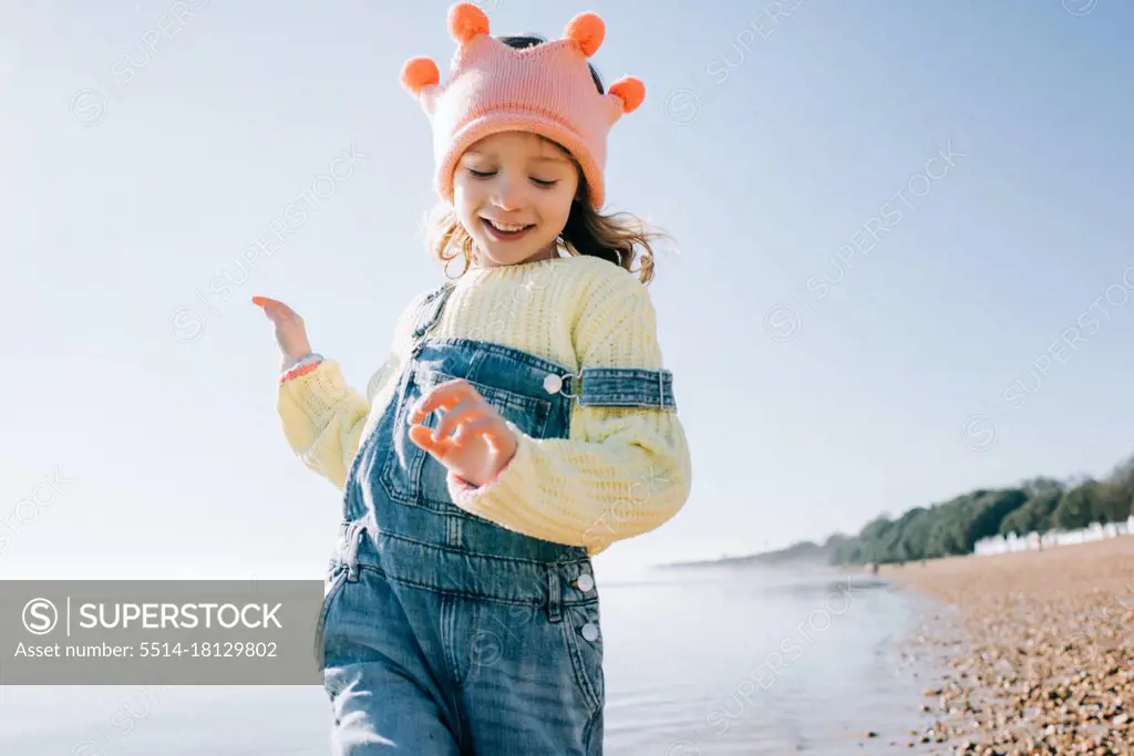 girl playfully running on the beach playing dress up in the sun