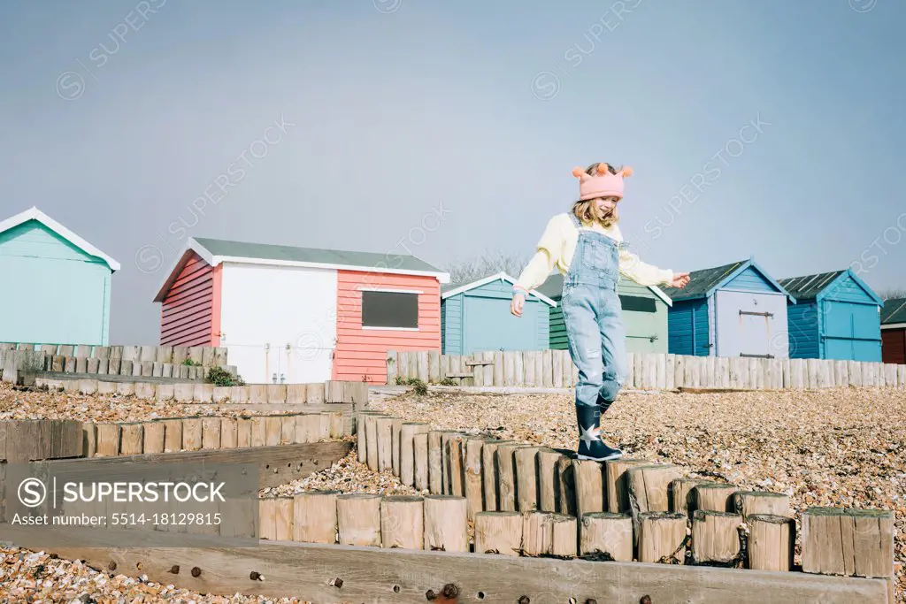 child playfully walking at the beach by colourful beach huts in the UK