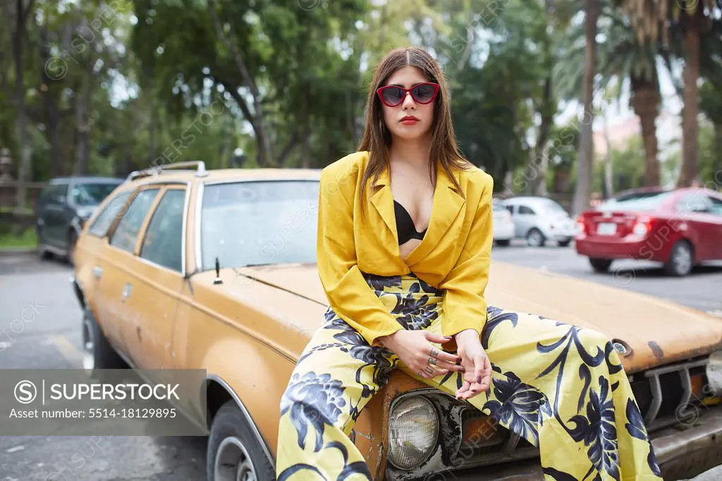 fashion confident young woman leaning on a car and looking at the car