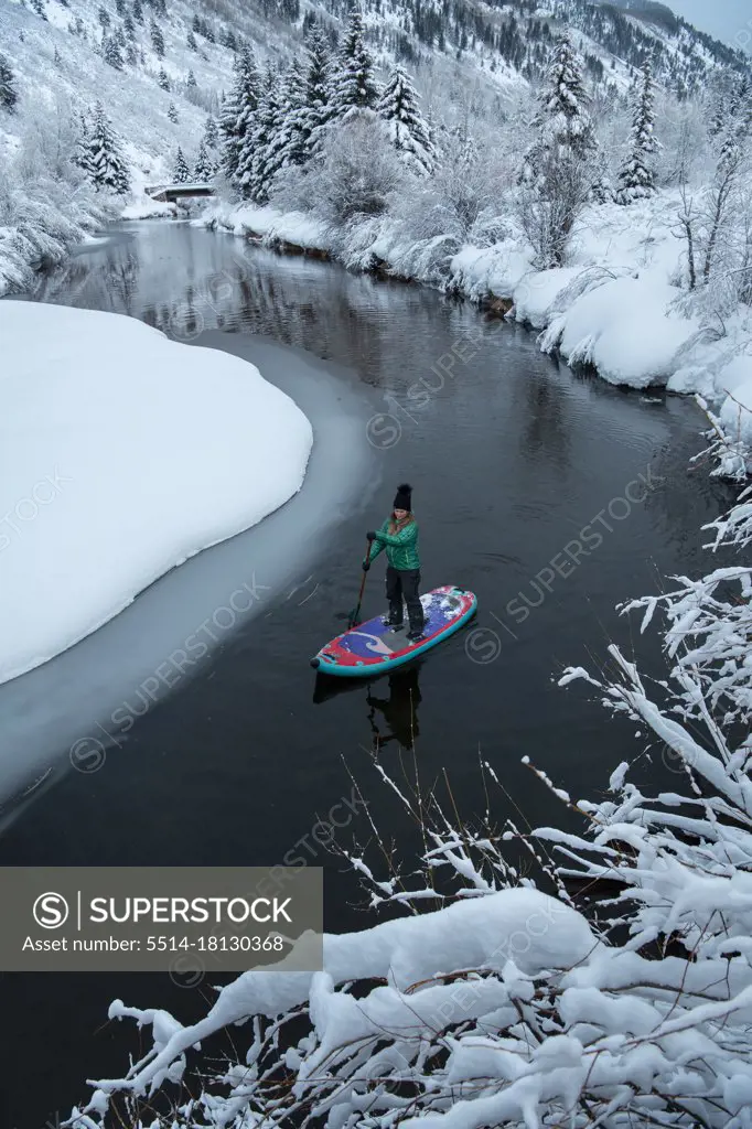 Woman paddleboarding on river during winter