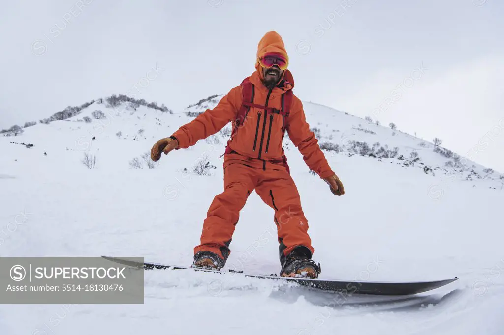 Smiling man snowboarding on snowcapped mountain in vacation