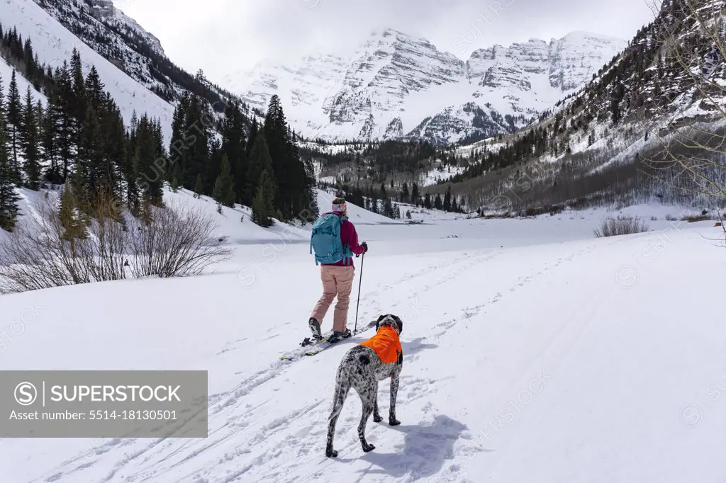 Young woman hiking with Pointer dog during winter