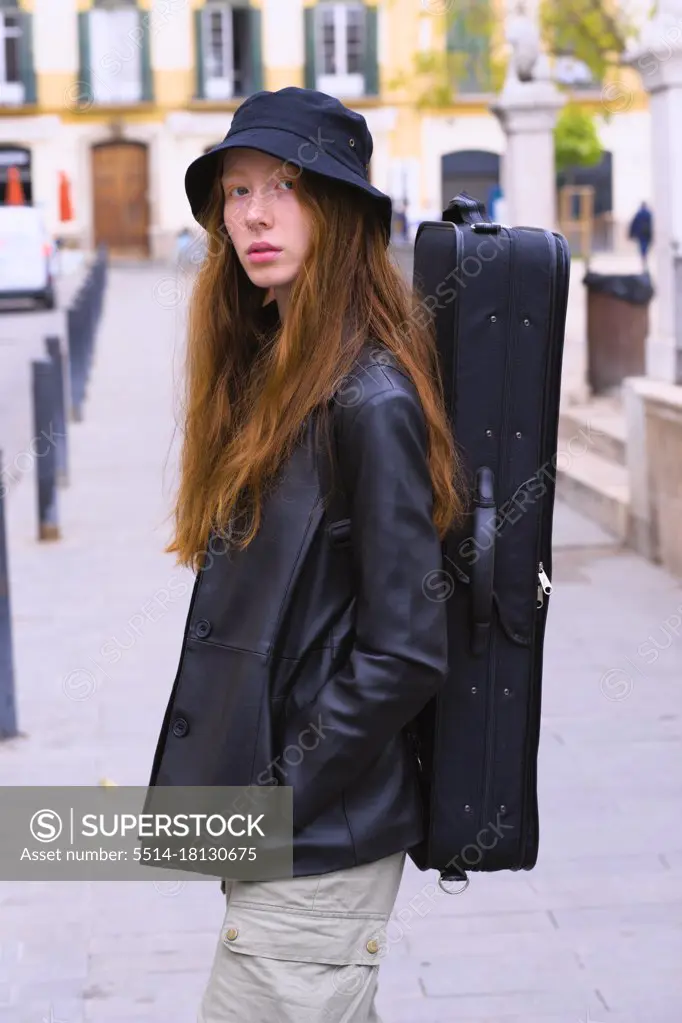 Young red-haired woman in the city streets with her backpack on