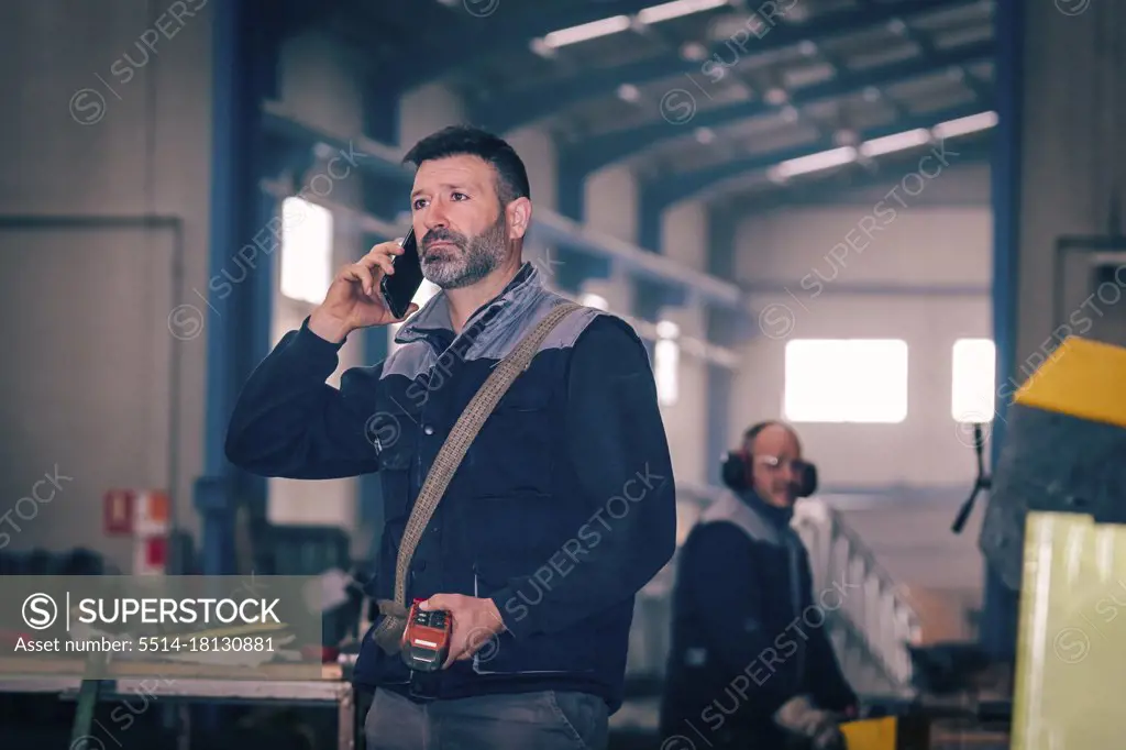 Man talking by telephone with the control of a bridge crane