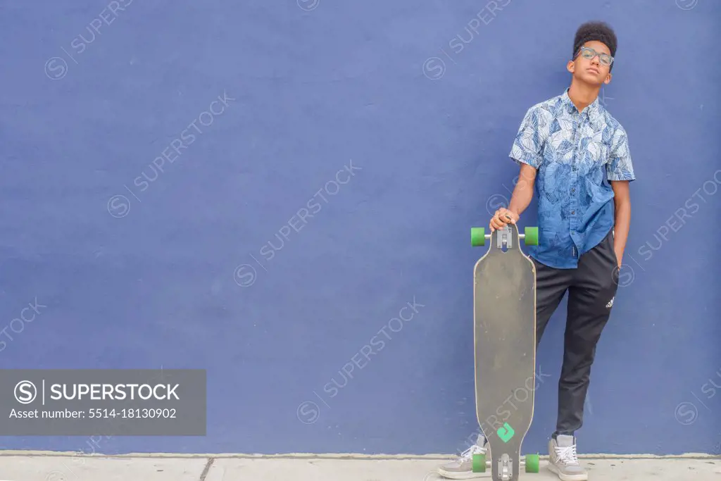 Skateboard teen against blue wall