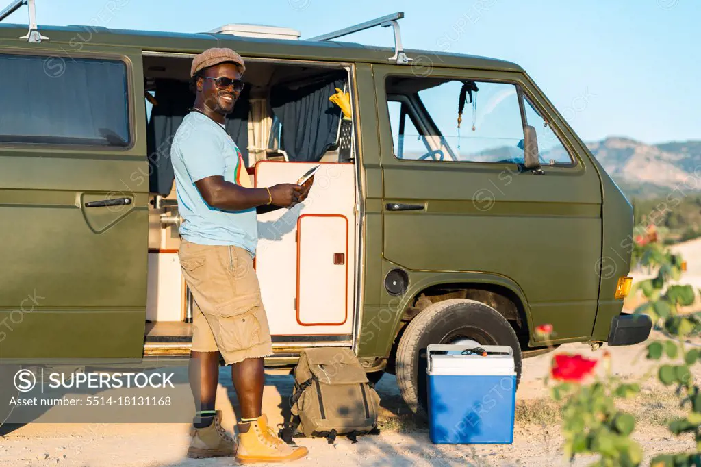 black man with glasses, and mobile phone in camper van