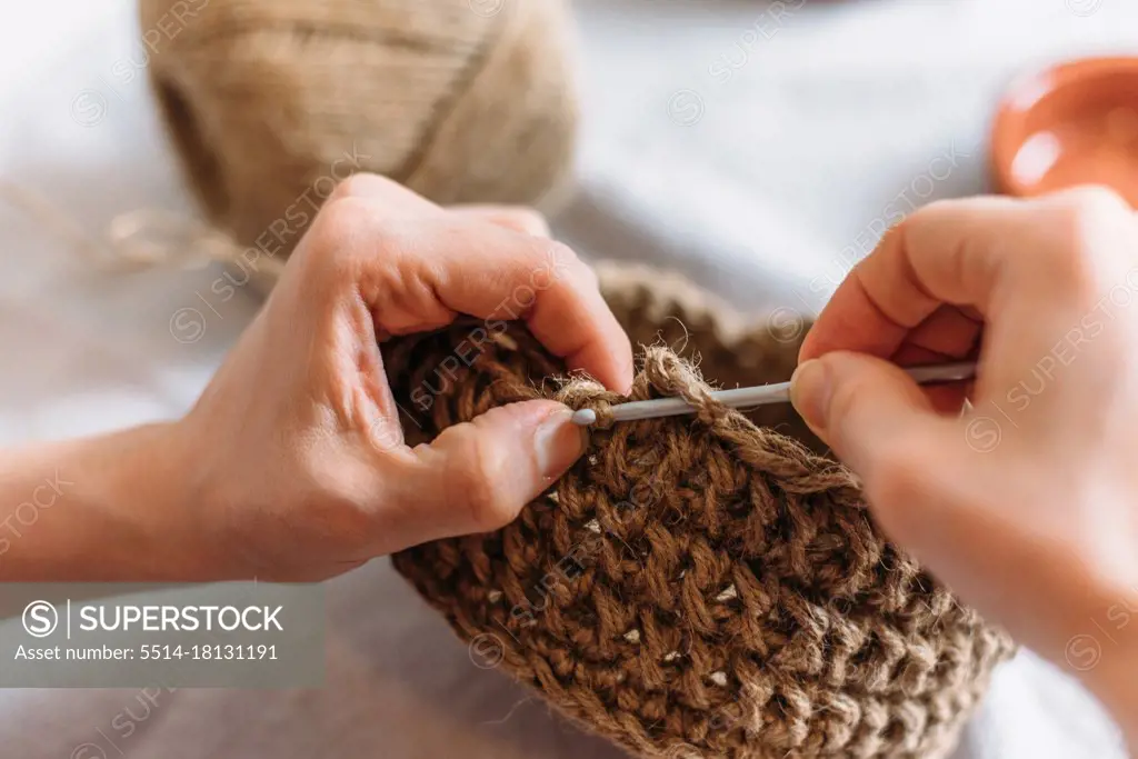 Close-up of woman's hands knitting from jute