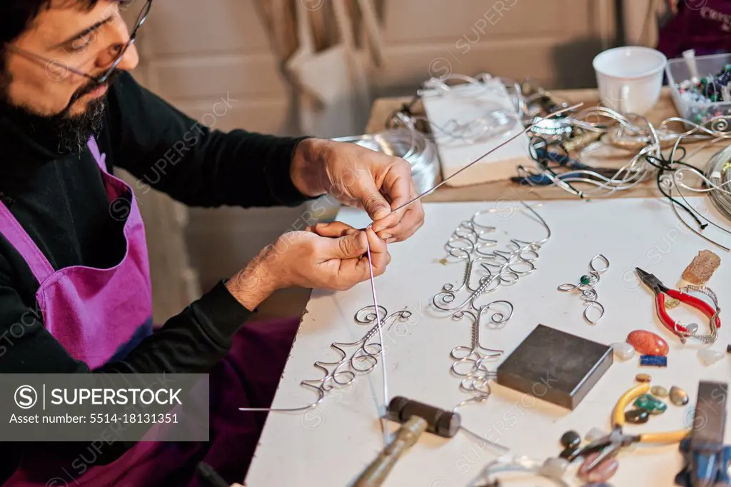 Jeweler craftsman working at table with work tools inside workshop