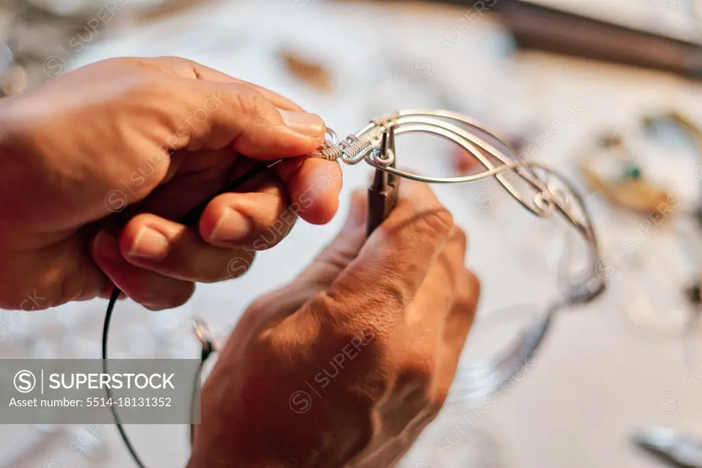 Hands of craftsman jeweler working at table with work tools inside workshop