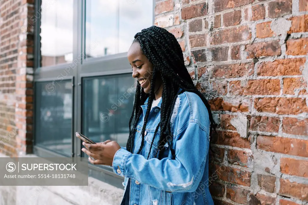 Young black woman scrolling on social media and holding her phone