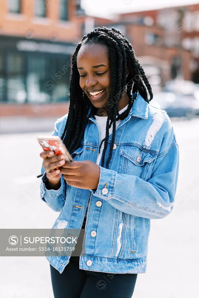 Young black woman scrolling online on social media on phone