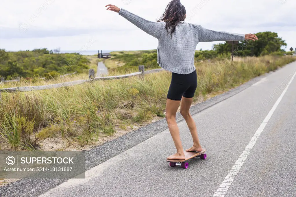 Young Woman skateboarding barefoot on overcast day