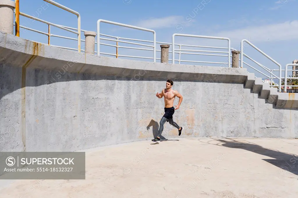 young man running shirtless outdoors