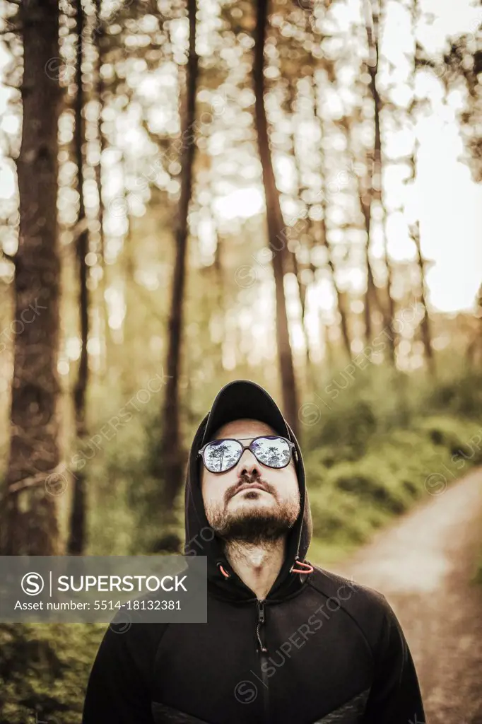 Man with sunglasses and hood in a beautiful forest
