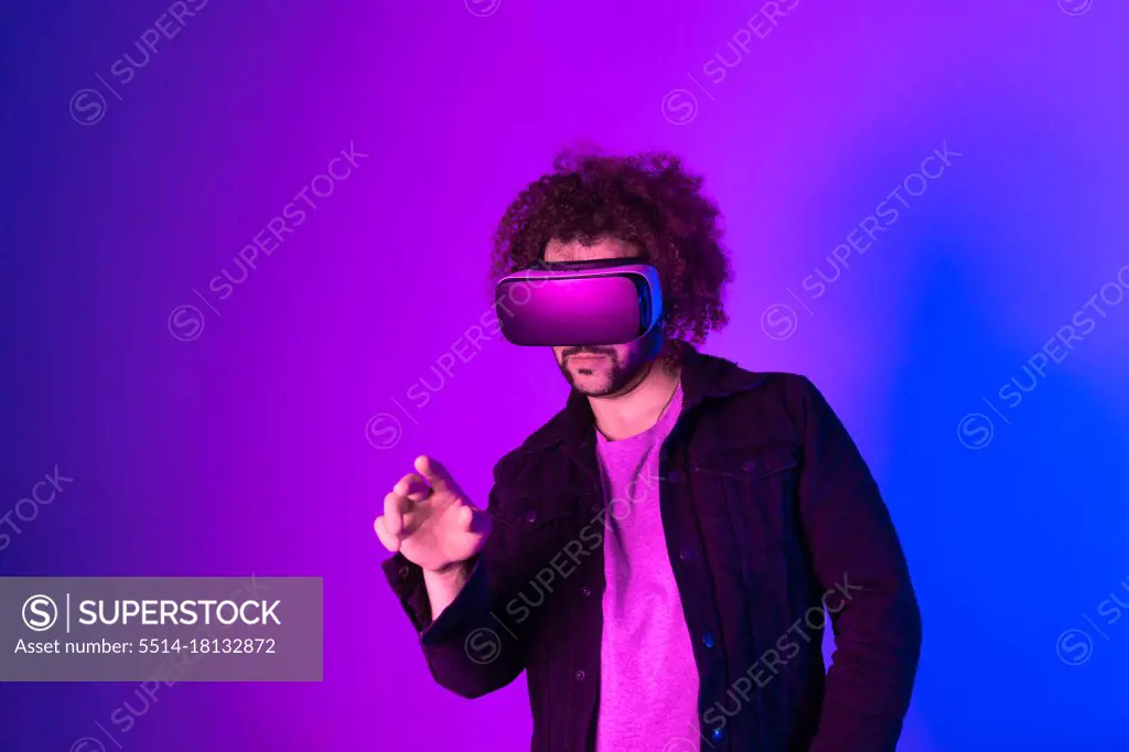 Hipster young man using virtual reality headset over blue purple