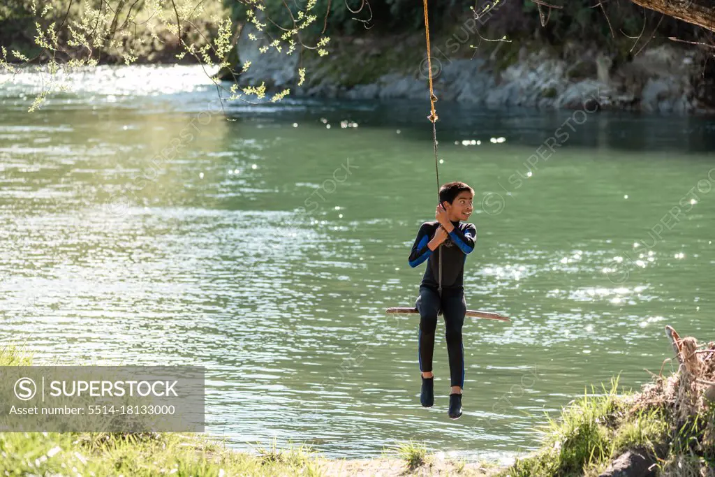 Young teenager on rope swing over river in New Zealand