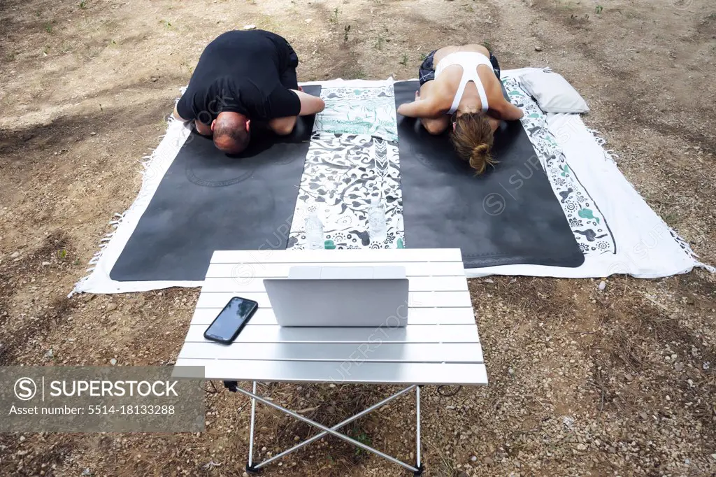 View from above relaxed couple crouching lying on yoga mat