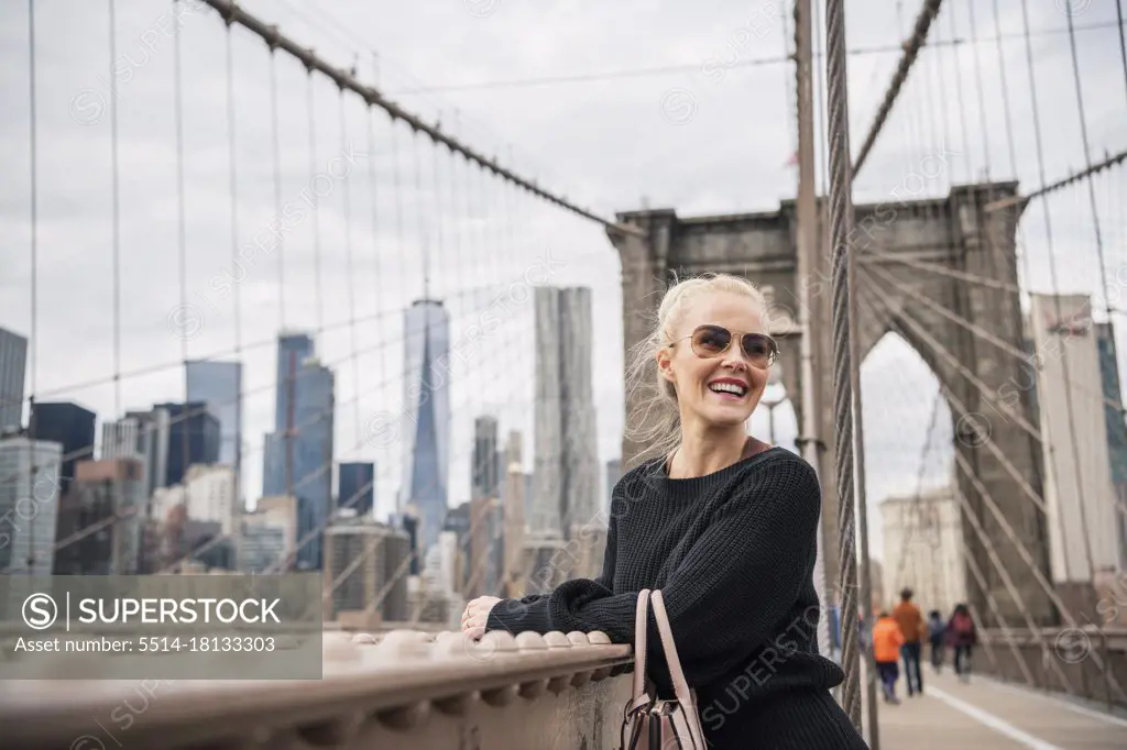 Delighted female tourist leaning on bridge railing