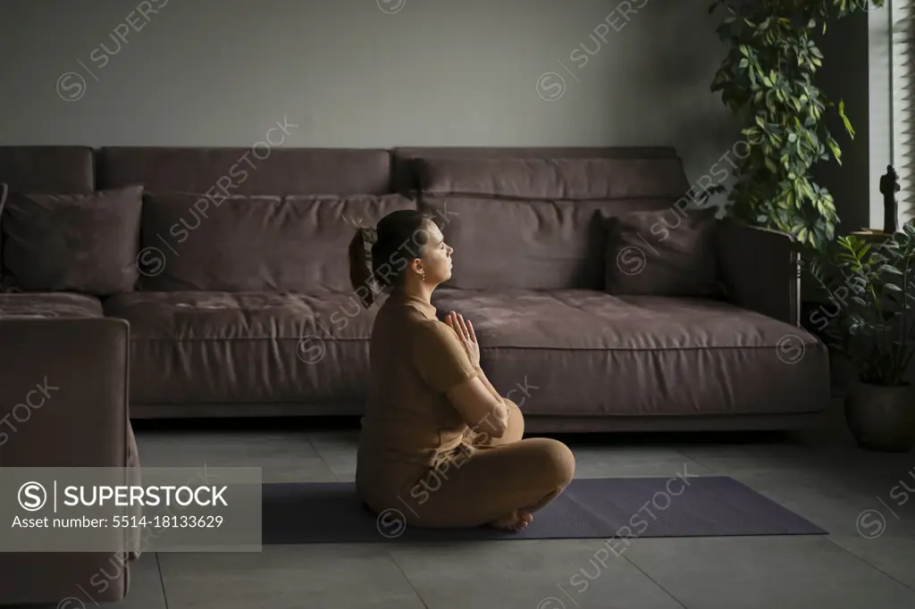 Body positive woman practicing yoga at home.