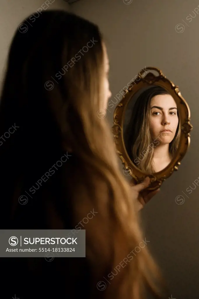 A woman looking at herself in a vintage mirror